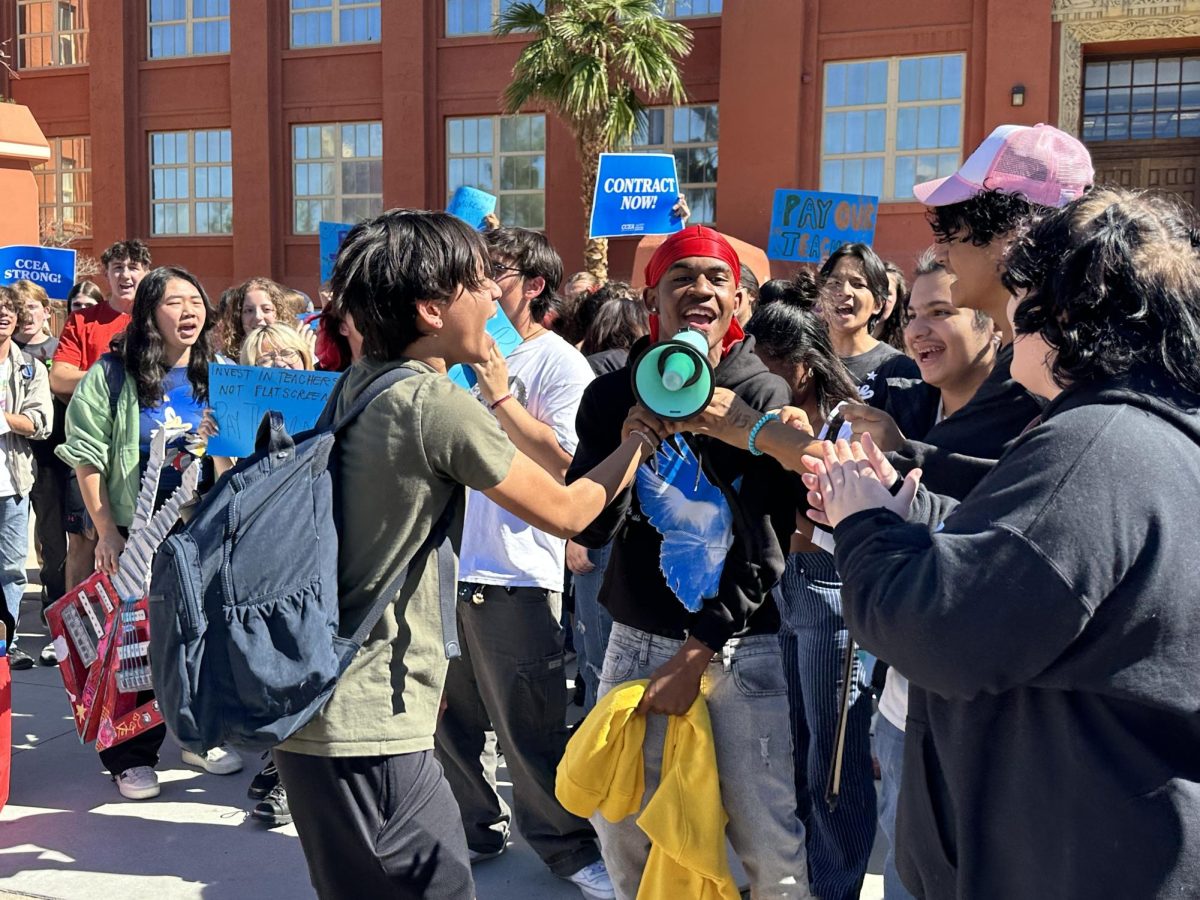 Junior Mo Throng Lima hands off a megaphone to students attending the walkout. 