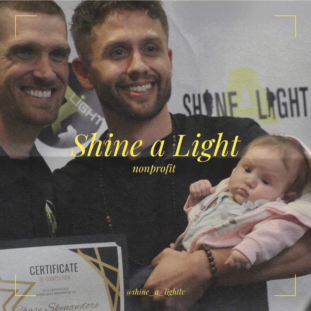 Shine a Light founder Paul Vautrinot smiles proudly with graduate and his infant at the organization’s IPATH program graduation. 
