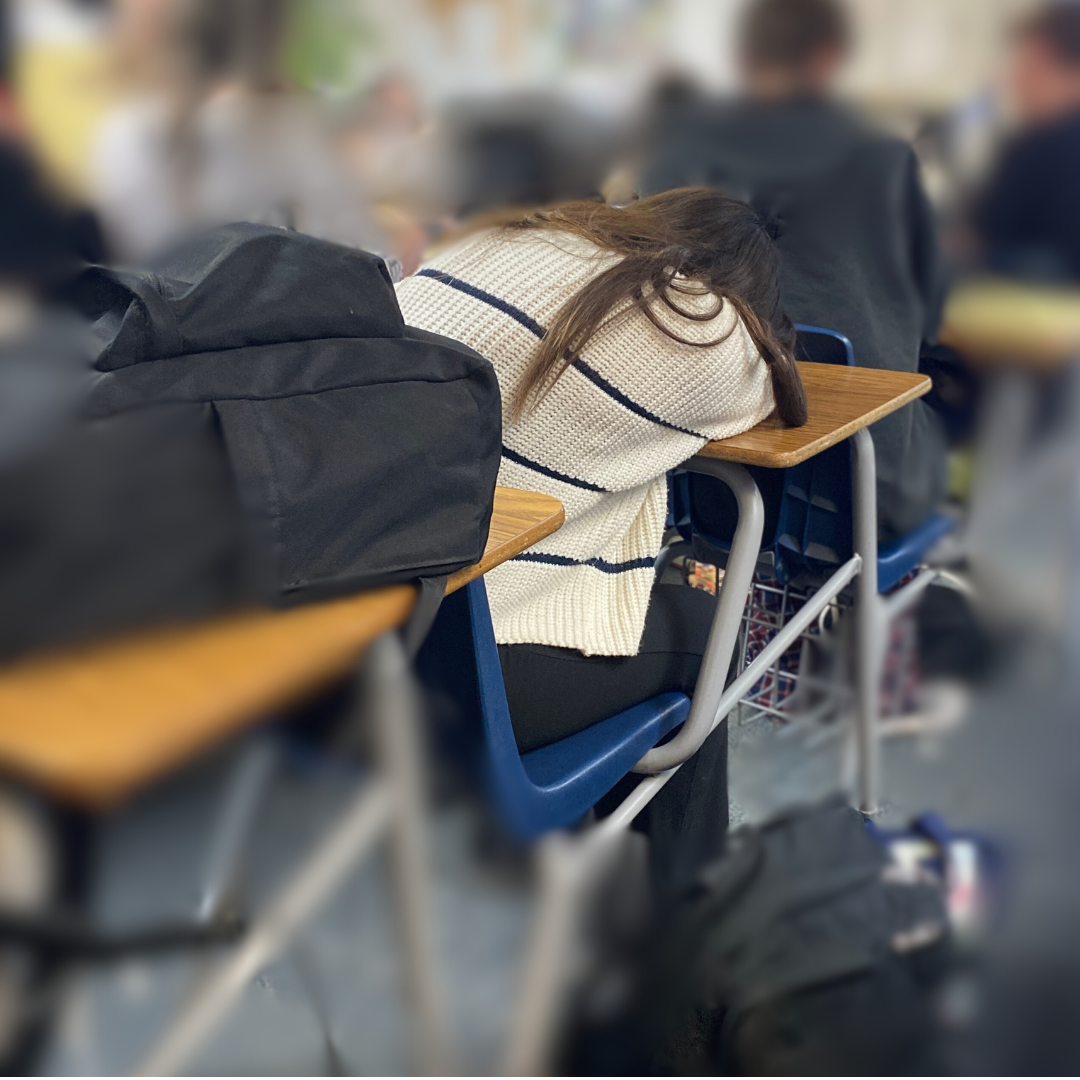 A student rests her head during instruction, feeling tired and overwhelmed.